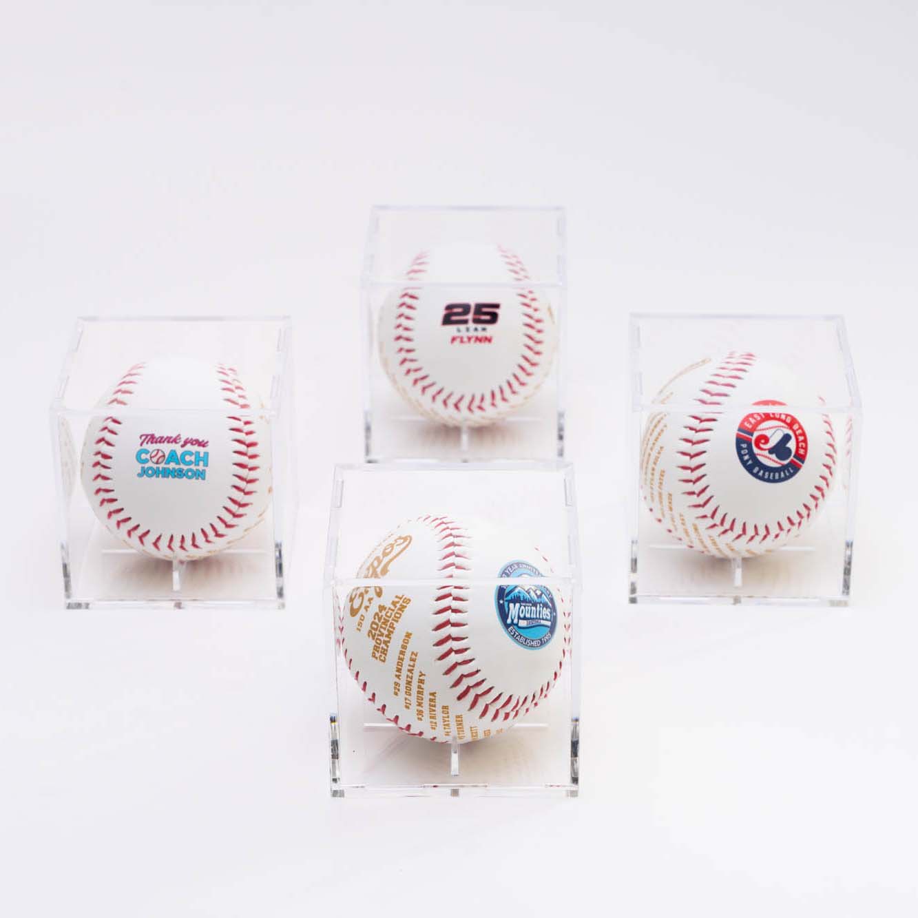 Four baseballs in acrylic cases on a white background