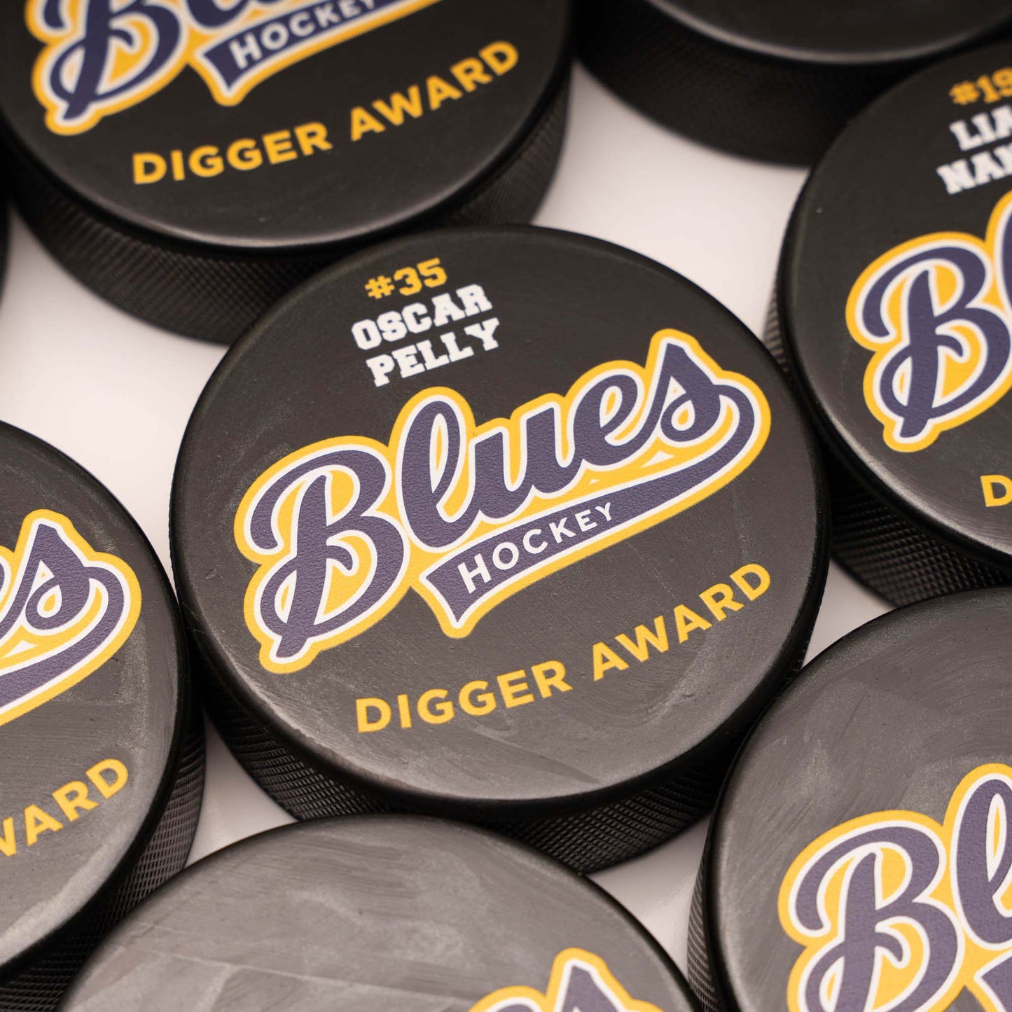 Hockey pucks with 'Blues Hockey' branding and text on a white background