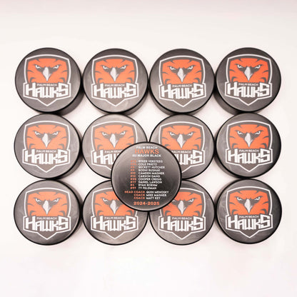 Collection of Palm Beach Hawks branded pucks on a white background
