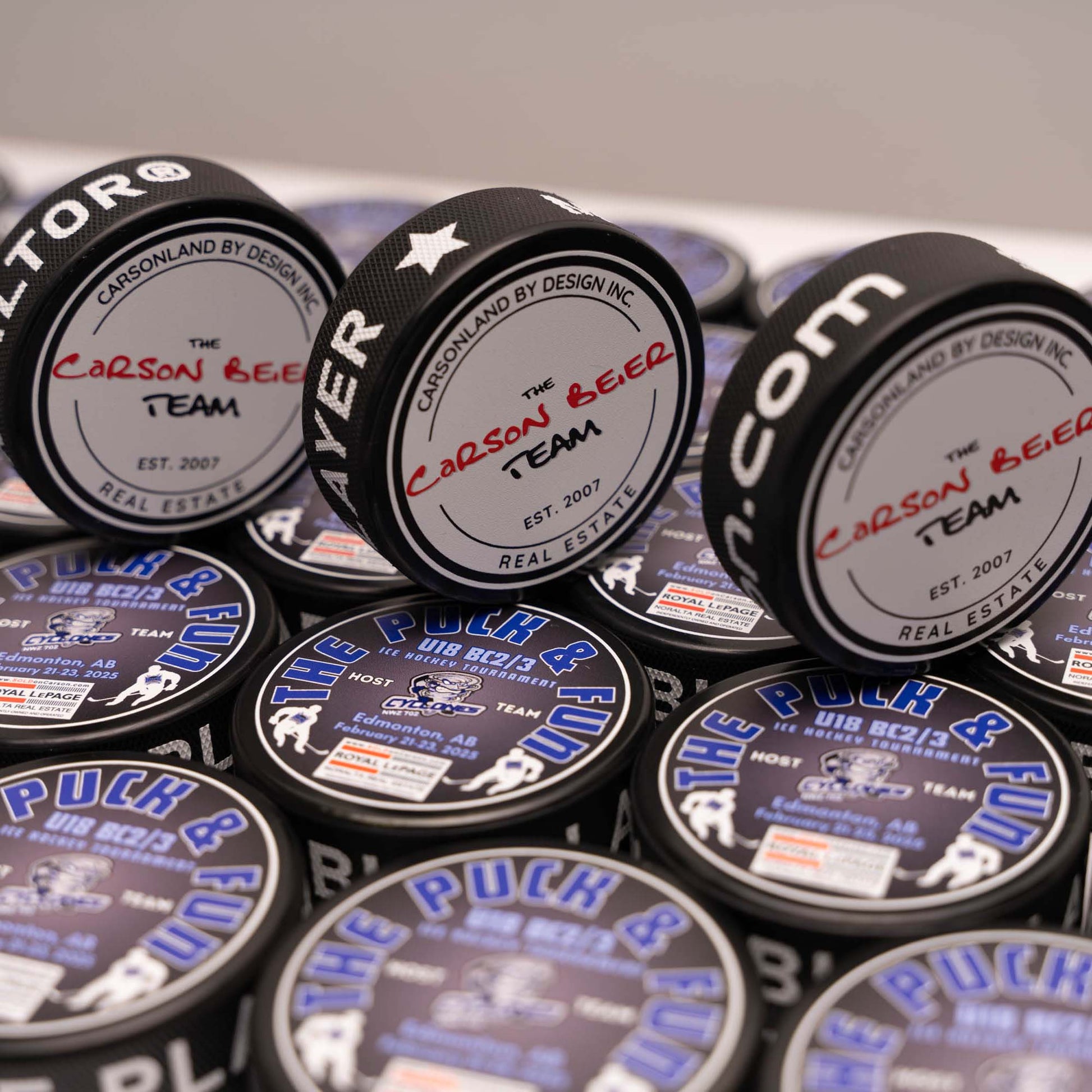 Collection of branded hockey pucks with various logos and text.