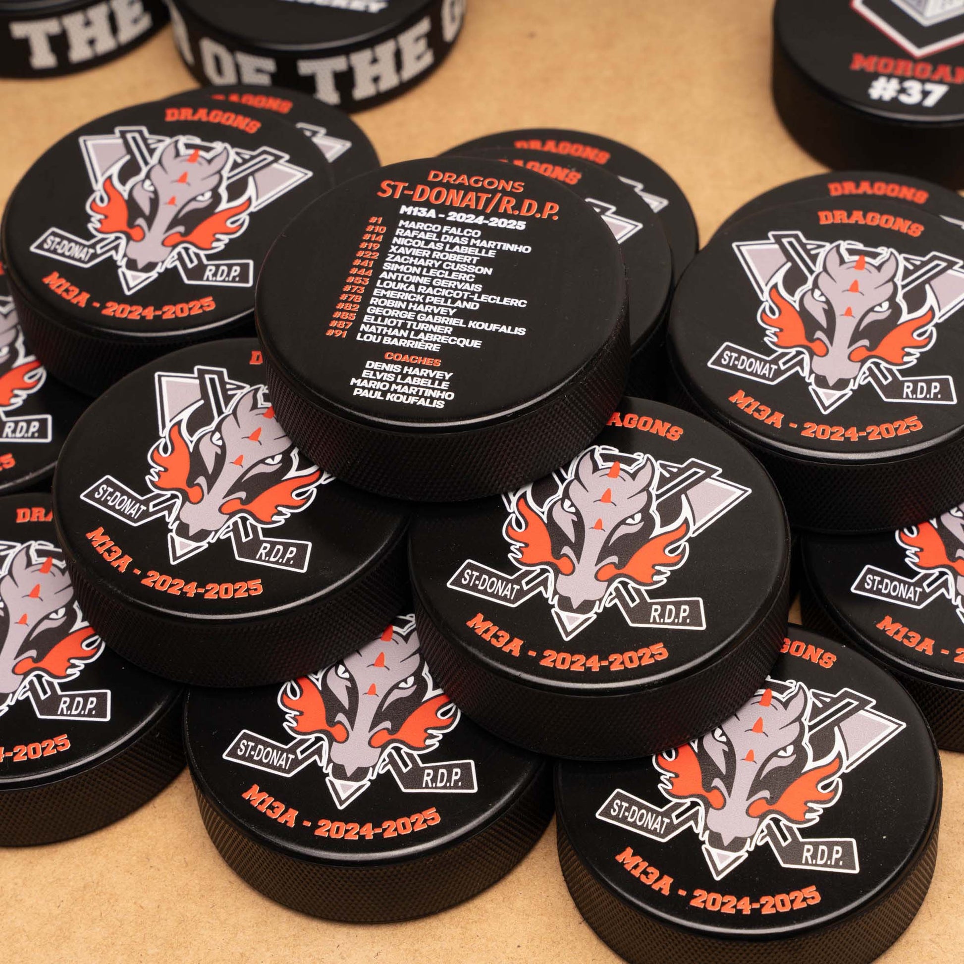 Collection of hockey pucks with dragon logo and team roster at the back