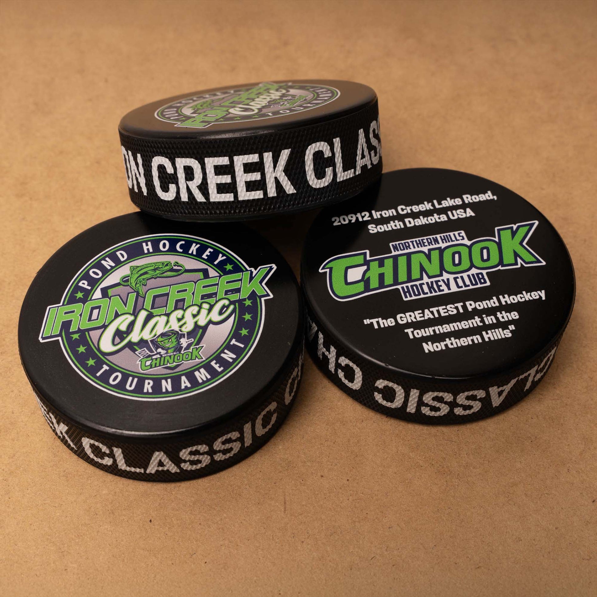 Three hockey pucks with Iron Creek Classic and Chinook logos
