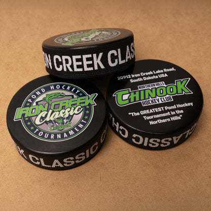 Three hockey pucks with Iron Creek Classic and Chinook logos