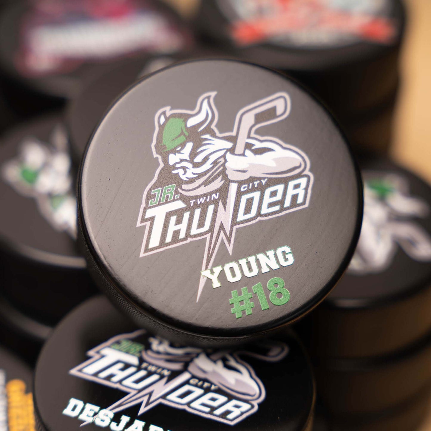 Puck with 'Jr. Twin City Thunder' logo and text on a blurred background