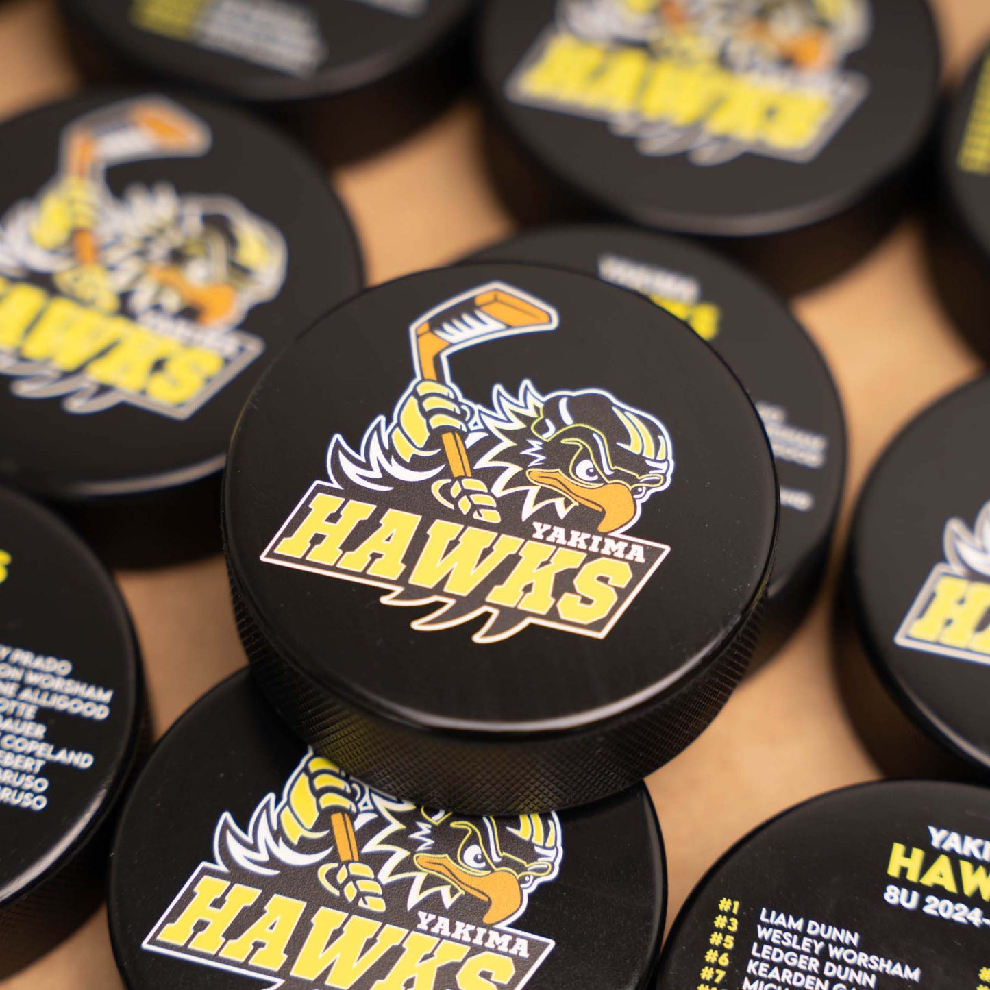 Pile of hockey pucks with Yakima Hawks logo and team roster