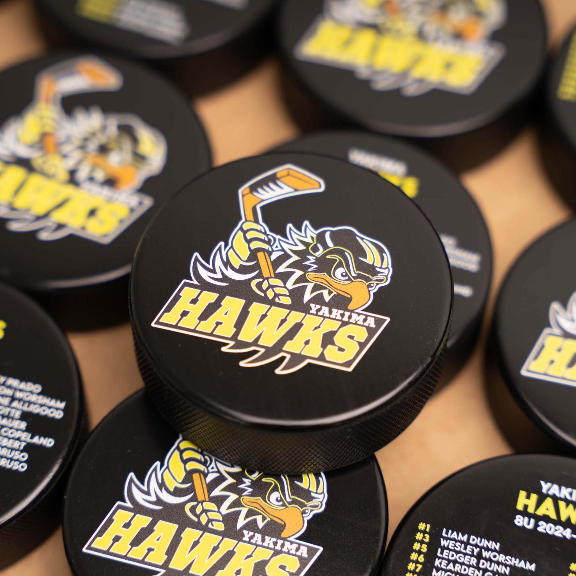 Pile of hockey pucks with Yakima Hawks logo and team roster