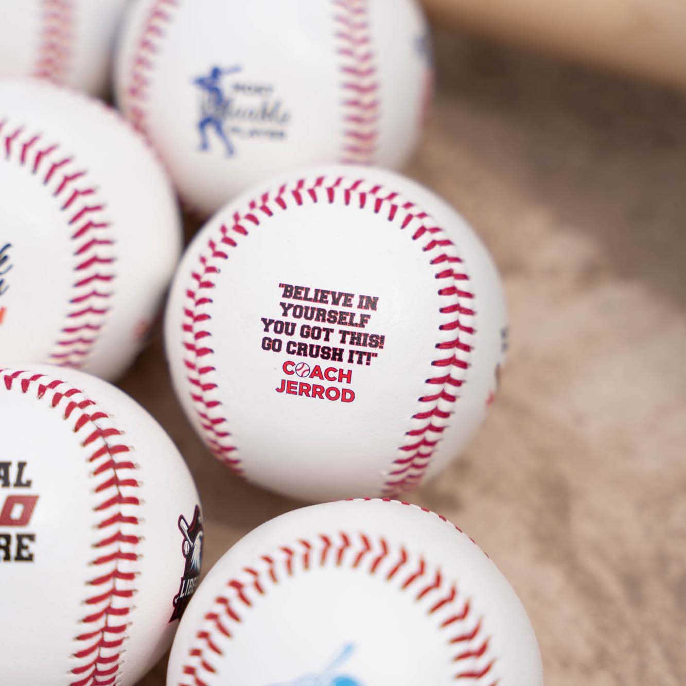 Baseballs with motivational messages and branding on a textured surface