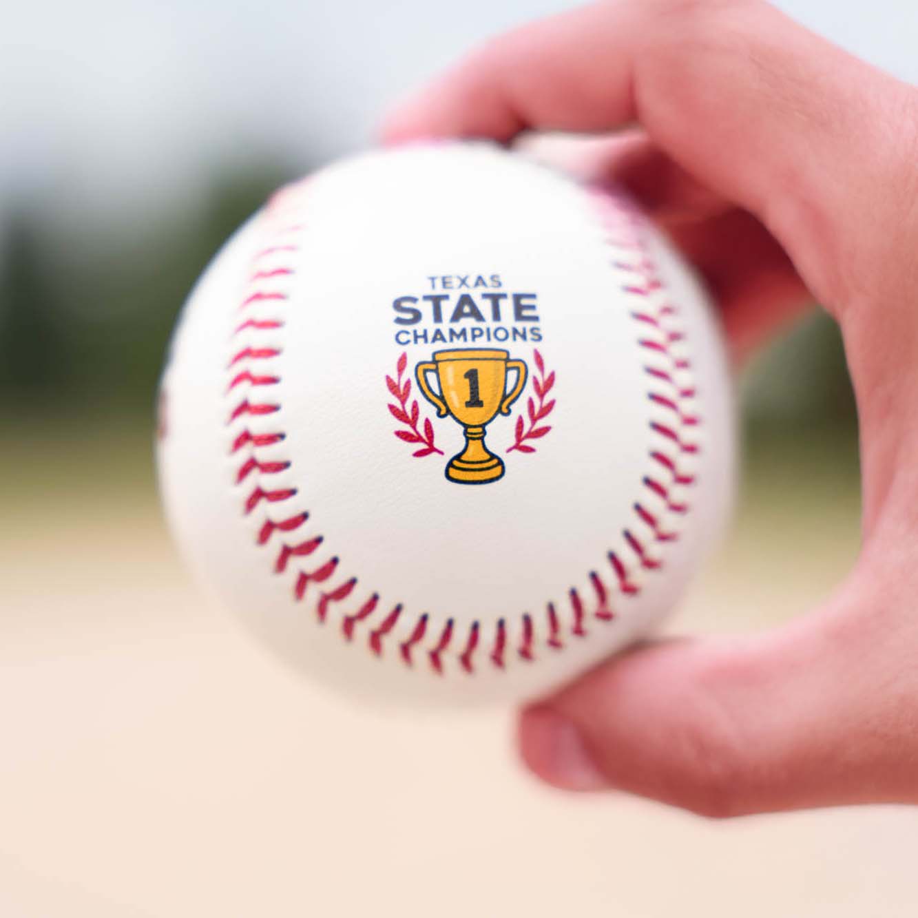 Baseball with 'Texas State Champions' and trophy graphic held by a hand