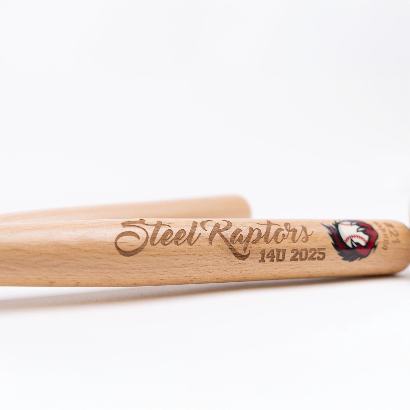 Two wooden mini baseball bats with 'Steel Raptors' and '14U 2025' engraved on the bat