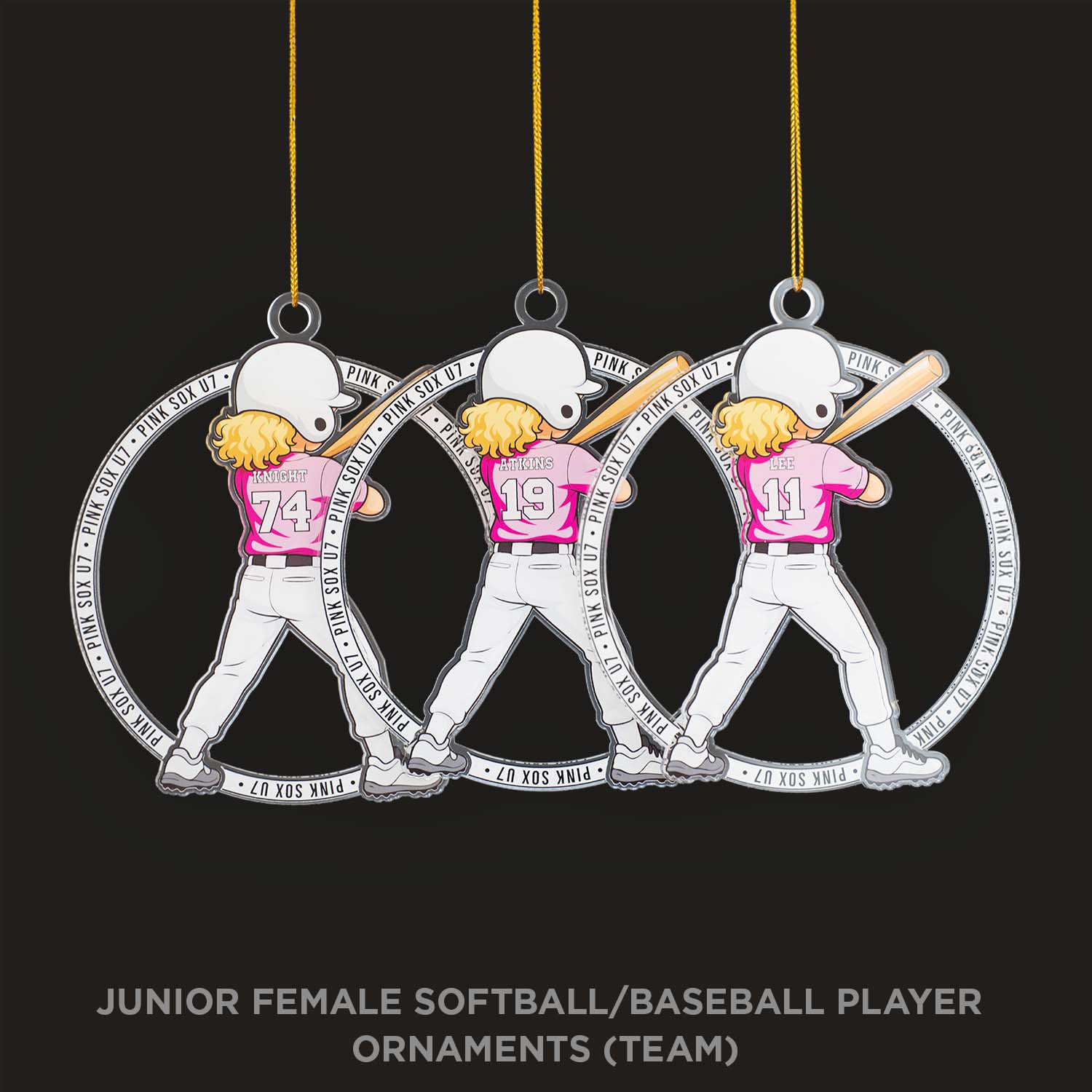 Three softball/baseball player ornaments hanging against a black background